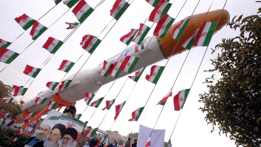 A boy holding a placard with pictures of (L-R) President Hassan Rouhani, the late founder of the Islamic Revolution Ayatollah Ruhollah Khomeini, and Iran's Supreme Leader Ayatollah Ali Khamenei, poses for camera in front of a model of Simorgh satellite-carrier rocket during a ceremony marking the 37th anniversary of the Islamic Revolution, in Tehran February 11, 2016. REUTERS/Raheb Homavandi/TIMAATTENTION EDITORS - THIS IMAGE WAS PROVIDED BY A THIRD PARTY. FOR EDITORIAL USE ONLY. - GF10000304511