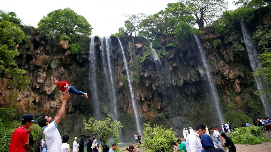 A tourist lifts up a boy as they visit waterfalls at Ayn Athum in Salalah, Dhofar province, Oman August 23, 2016. Picture taken August 23, 2016. REUTERS/Ahmed Jadallah  - D1BETYFAUFAC