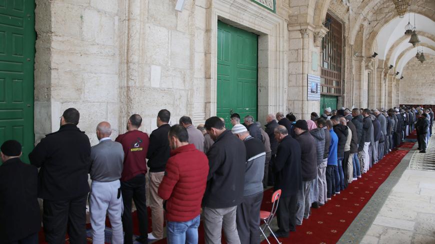 JERUSALEM - MARCH 15: Muslims perform prayer outside the Al-Aqsa Mosque after the Islamic Waqf Department announced to close the enclosed prayer places as a precautionary measure to prevent the spread of the coronavirus (COVID-19) outbreak in Jerusalem on March 15, 2020. According to the statement, all prayers remain to be held in the [outdoor] courtyard and all doors will be open to worshipers. (Photo by Mostafa Alkharouf/Anadolu Agency via Getty Images)