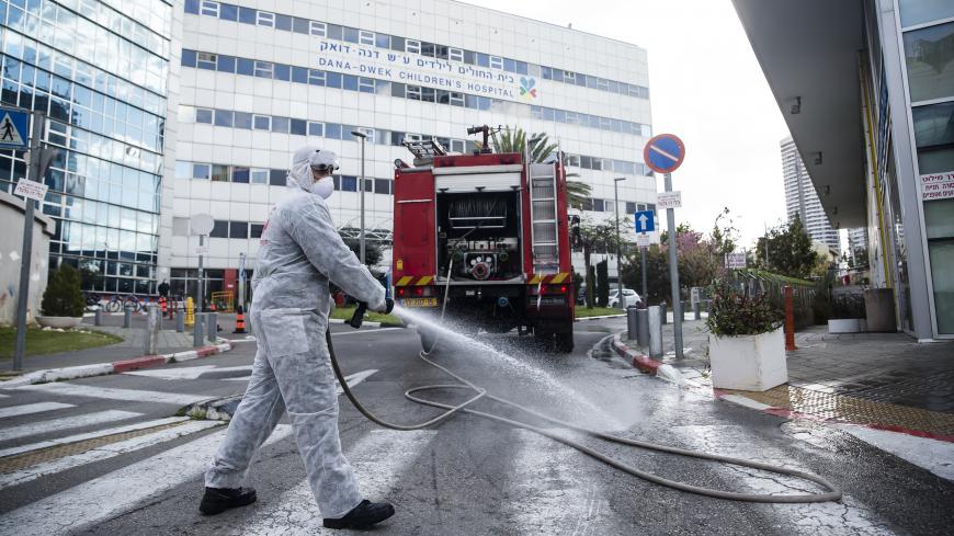 TEL AVIV, ISRAEL - MARCH 20: An Israeli Fire Department crew man sprays disinfectants as he sanitize the entrance to Tel Aviv's Hospital children department on March 20, 2020 in Tel Aviv, Israel. Number of coronavirus in Israel continues to jump, after over 200 new cases have been diagnosed with COVID-19 in the past 24 hours.  (Photo by Amir Levy/Getty Images)