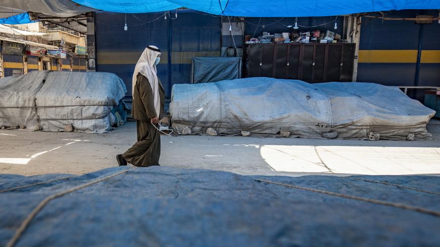 A man wearing a protective mask walks by at an empty market in the Kurdish-majority city of Qamishli in Syria's northeastern Hasakah province, on March 23, 2020, amid measures to curb the spread of the novel coronavirus. - The Kurdish authorities in northeast Syria have not recorded any deaths so far, but have imposed a curfew in a bid to stem any outbreak. (Photo by DELIL SOULEIMAN / AFP) (Photo by DELIL SOULEIMAN/AFP via Getty Images)
