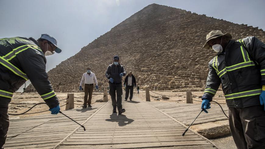 TOPSHOT - Egyptian municipality workers disinfect the Giza pyramids necropolis on the southwestern outskirts of the Egyptian capital Cairo on March 25, 2020 as protective a measure against the spread of the coronavirus COVID-19. (Photo by Khaled DESOUKI / AFP) (Photo by KHALED DESOUKI/AFP via Getty Images)