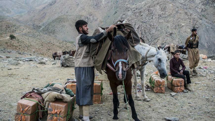 ZAGROS, IRAQ - JULY 27: A Kurdish-Iranian smuggler packs his horse in preparation to carry goods over the Iraq border into Iran on July 27, 2017 in the Zagros Mountains, northern Iraq. (Photo by Martyn Aim/Corbis via Getty Images)