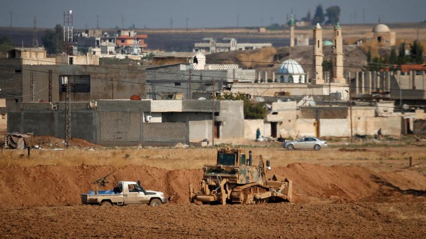 A vehicle belonging to Turkey-backed Syrian rebel fighters is parked next to a Turkish military bulldozer in the Syrian town of Ras al Ain, as seen from the Turkish border town of Ceylanpinar, in Sanliurfa province, Turkey, October 30, 2019. REUTERS/Kemal Aslan - RC121F436090