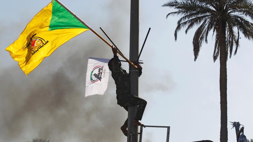 A member of Hashd al-Shaabi (paramilitary forces) holds a flag of Kataib Hezbollah militia group during a protest to condemn air strikes on their bases, in Baghdad, Iraq December 31, 2019. REUTERS/Khalid al-Mousily - RC2E6E9TSWK4