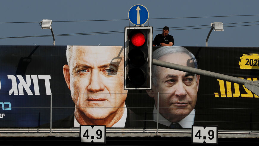 A labourer hangs a banner depicting Israeli Prime Minister Benjamin Netanyahu and Benny Gantz, leader of Blue and White party, as part of the party's campaign ahead of the upcoming election, in Tel Aviv, Israel February 17, 2020. REUTERS/Ammar Awad - RC292F9SWH47