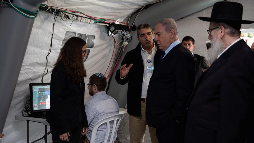 Israeli Prime Minister Benjamin Netanyahu arrives to a tent during his visit to the Chaim Sheba Medical Center at Tel Hashomer in Ramat Gan, Israel, for discussion on the coronavirus, February 19, 2020. Heidi Levine/Poolvia REUTERS - RC2N3F92AZM9