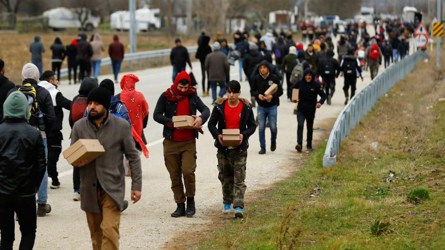 Migrants walk with boxes of food delivered by members of United Nations High Commissioner for Refugees at the Turkey's Pazarkule border crossing with Greece's Kastanies, in Edirne, Turkey, February 29, 2020. REUTERS/Huseyin Aldemir - RC2FAF9OGDW7