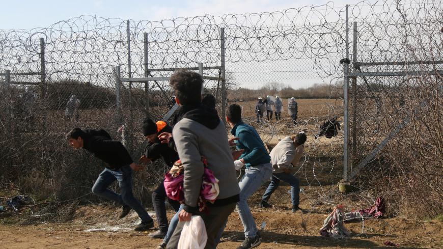 Migrants throw stones at a Greek military vehicle on the Turkish-Greek border at Turkey's Pazarkule border crossing with Greece's Kastanies, near Edirne, Turkey, March 2, 2020. REUTERS/Cansu Alkaya - RC2OBF93OREA