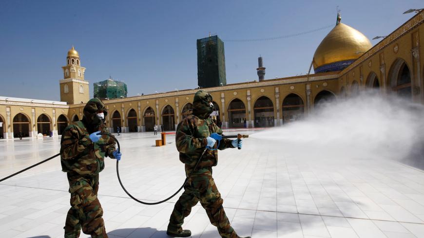 Members of the civil defense team spray disinfectant to sanitize surrounding of the Kufa mosque, following an outbreak of the coronavirus, in the holy city of Najaf, Iraq February 27, 2020. Picture taken February 27, 2020.  REUTERS/Alaa al-Marjani - RC2RDF9QBKYW
