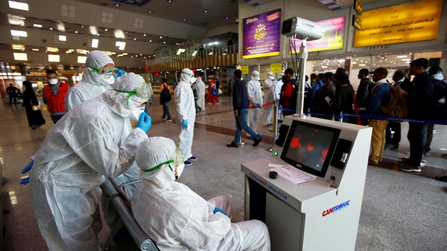 Medical staff in protective gear look at a screen while checking temperatures of passengers upon their arrival, following an outbreak of the coronavirus, at Najaf airport, in the holy city of Najaf, Iraq February 26, 2020. Picture taken February 26, 2020.  REUTERS/Alaa al-Marjani - RC2RDF9PKKES