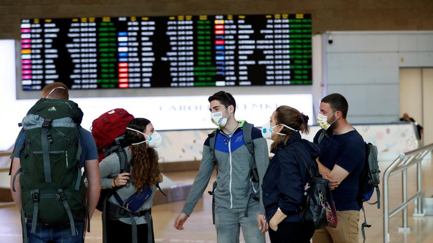 Travelers wearing masks chat in the arrivals terminal after Israel said it will require anyone arriving from overseas to self-quarantine for 14 days as a precaution against the spread of coronavirus, at Ben Gurion International airport in Lod, near Tel Aviv, Israel March 10, 2020. REUTERS/Ronen Zvulun - RC2WGF9S9SQ2