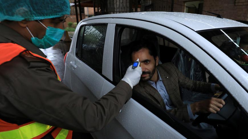A rescue worker wears protective hand gloves as he checks a man?s temperature amid coronavirus fears, at the entrance of the government office building in Peshawar, Pakistan March 12, 2020. REUTERS/Fayaz Aziz - RC26IF9CRNEA