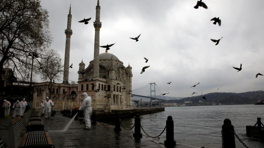 A worker sprays disinfectant outside Ortakoy Mosque, to prevent the spread of coronavirus disease (COVID-19), in Istanbul, Turkey, March 23, 2020. REUTERS/Umit Bektas - RC2MPF983853