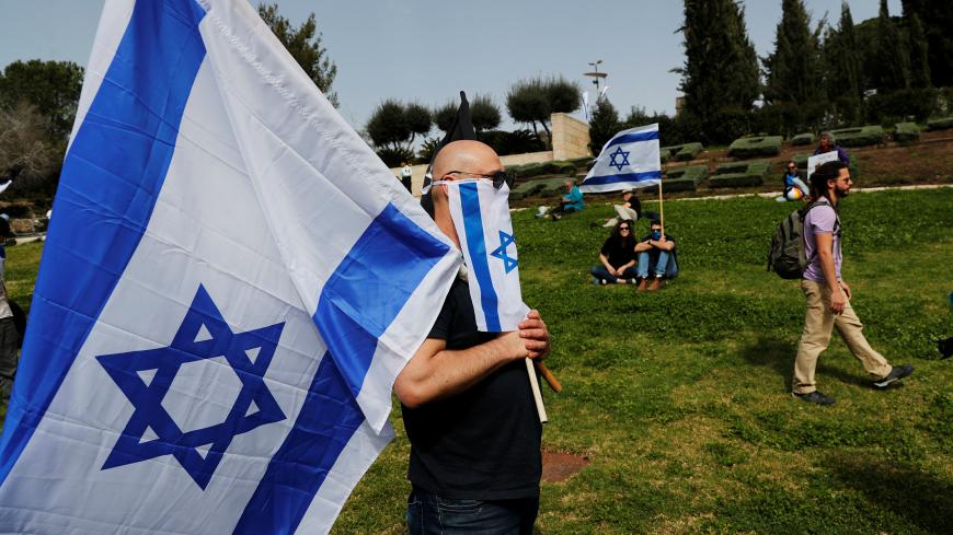 Israelis hold national flags during a demonstration against Prime Minister Benjamin Netanyahu's caretaker government, accusing it of undemocratic measures, outside the parliament in Jerusalem March 23, 2020 REUTERS/Ronen Zvulun - RC2QPF9E73ES