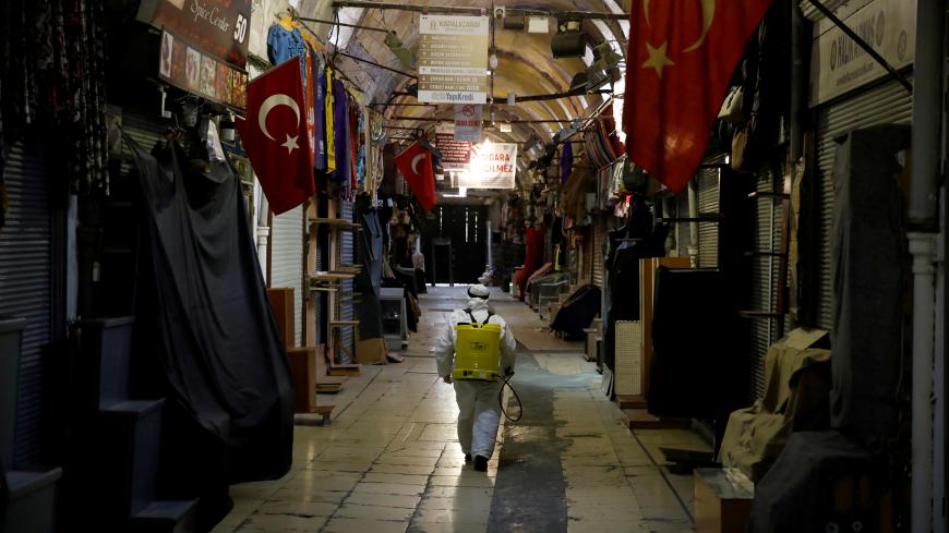 A worker in a protective suit sprays disinfectant at Grand Bazaar, known as the Covered Bazaar, to prevent the spread of coronavirus disease (COVID-19), in Istanbul, Turkey, March 25, 2020. REUTERS/Umit Bektas     TPX IMAGES OF THE DAY - RC2YQF9U548J