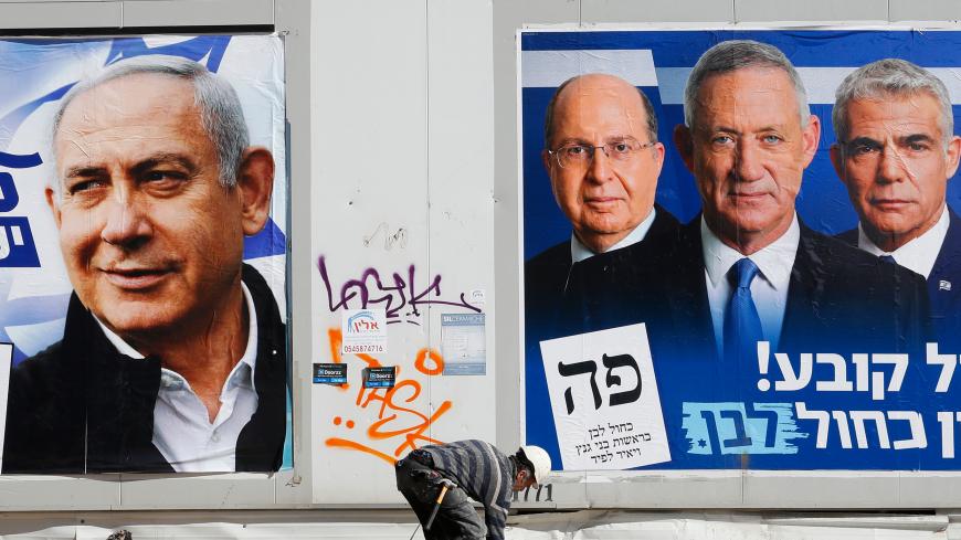 A labourer walks past electoral campaign posters bearing the portraits of Israel's Prime Minister Benjamin Netanyahu (L), leader of the Likud party, and retired Israeli general Benny Gantz (R), one of the leaders of the Blue and White (Kahol Lavan) political alliance, in the Israeli city of Tel Aviv, on April 3, 2019, ahead of the general election scheduled for April 9. (Photo by JACK GUEZ / AFP)        (Photo credit should read JACK GUEZ/AFP via Getty Images)