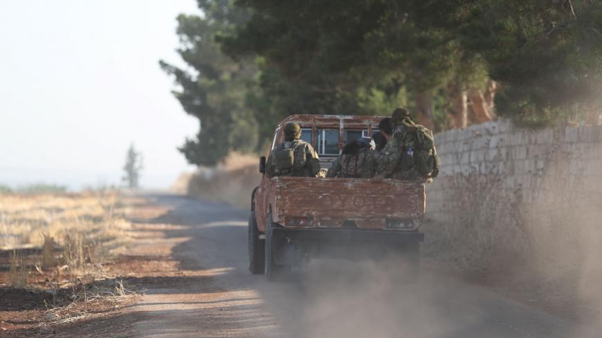 Fighters from the former al-Qaeda Syrian affiliate Hayat Tahrir al-Sham (HTS) drive through the village of Hamameyat on the border between Hama and Idlib provinces on July 11, 2019. - Regime and jihadist-led forces were locked in clashes on the edge of the opposition bastion in northwest Syria on July 11, after a jihadist-led advance that killed dozens of fighters overnight. Russian and regime aircraft have ramped up their deadly bombardment of the Idlib region -- administered by HTS, and home to some three