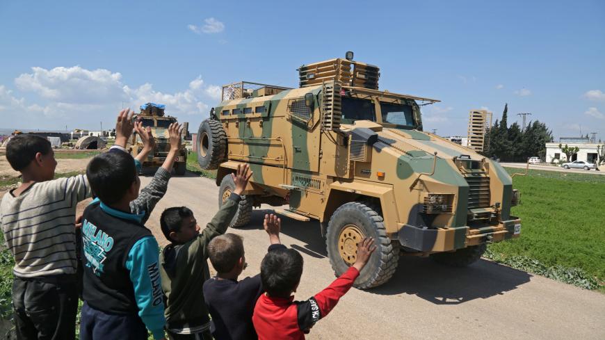 Syrian youths wave to a convoy of Turkish military reinforcements advancing near the town of Hazano in the countryside of Syria's Idlib province, on April 12, 2020, on the highway linking the Bab al-Hawa border crossing with Turkey to Idlib. (Photo by Aref TAMMAWI / AFP) (Photo by AREF TAMMAWI/AFP via Getty Images)