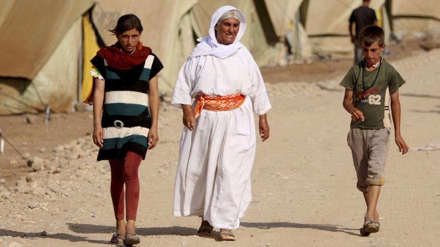 Refugees from the minority Yazidi sect, who fled the violence in the Iraqi town of Sinjar, walk past tents at Nowruz refugee camp in Qamishli, northeastern Syria, August 17, 2014. Proclaiming a caliphate straddling parts of Iraq and Syria, Islamic State militants have swept across northern Iraq, pushing back Kurdish regional forces and driving tens of thousands of Christians and members of the Yazidi religious minority from their homes. Picture taken August 17, 2014. REUTERS/Rodi Said   (SYRIA - Tags: POLIT
