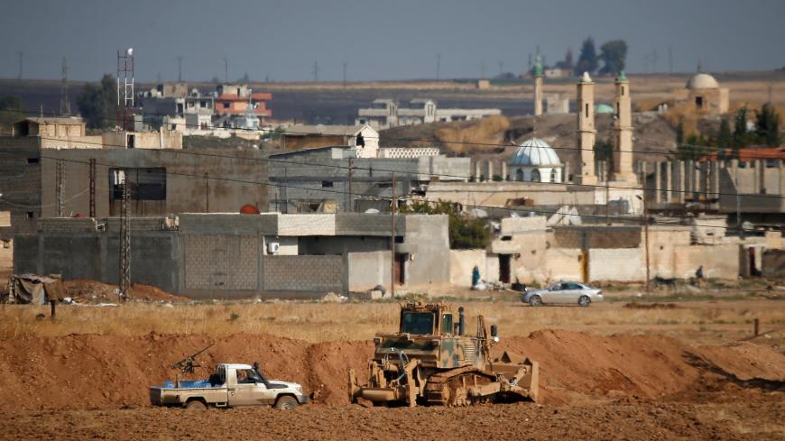 A vehicle belonging to Turkey-backed Syrian rebel fighters is parked next to a Turkish military bulldozer in the Syrian town of Ras al Ain, as seen from the Turkish border town of Ceylanpinar, in Sanliurfa province, Turkey, October 30, 2019. REUTERS/Kemal Aslan - RC121F436090