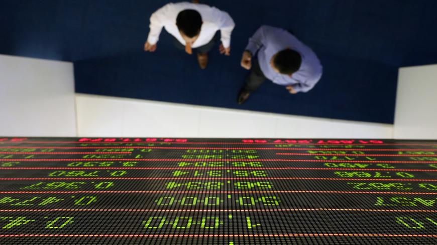 Investors walk under a stock index board at the Dubai Financial Market in Dubai, United Arab Emirates, January 8, 2020. REUTERS/Christopher Pike - RC2NBE9J9TZ4
