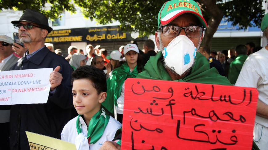A demonstrator wearing a face mask carries a placard that reads: "The authority and its supporters are deadlier than the Coronavirus " during an anti-government protest in Algiers, Algeria February 28, 2020.  REUTERS/Ramzi Boudina - RC2S9F9KLXXC