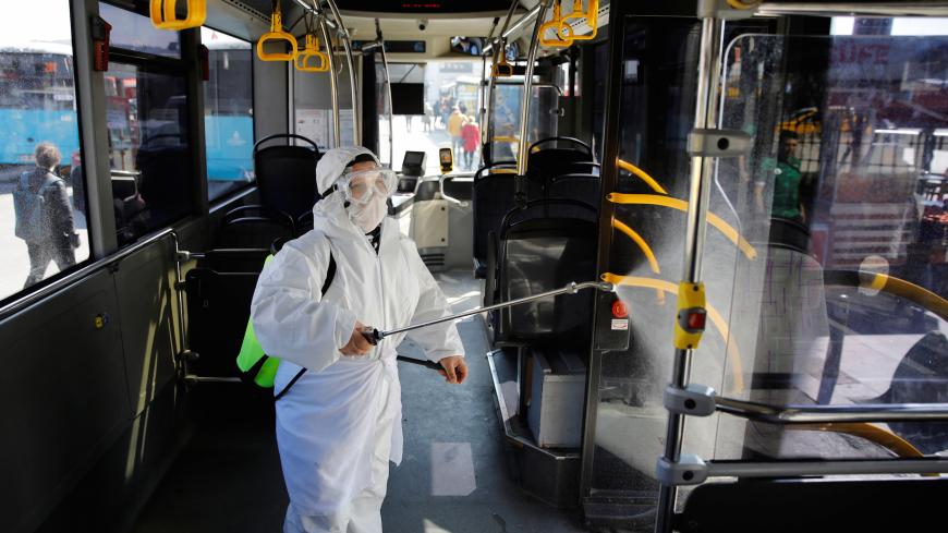 A worker in a protective suit disinfects a bus due to coronavirus concerns in Istanbul, Turkey March 11, 2020. REUTERS/Umit Bektas - RC2SHF9JD2JM