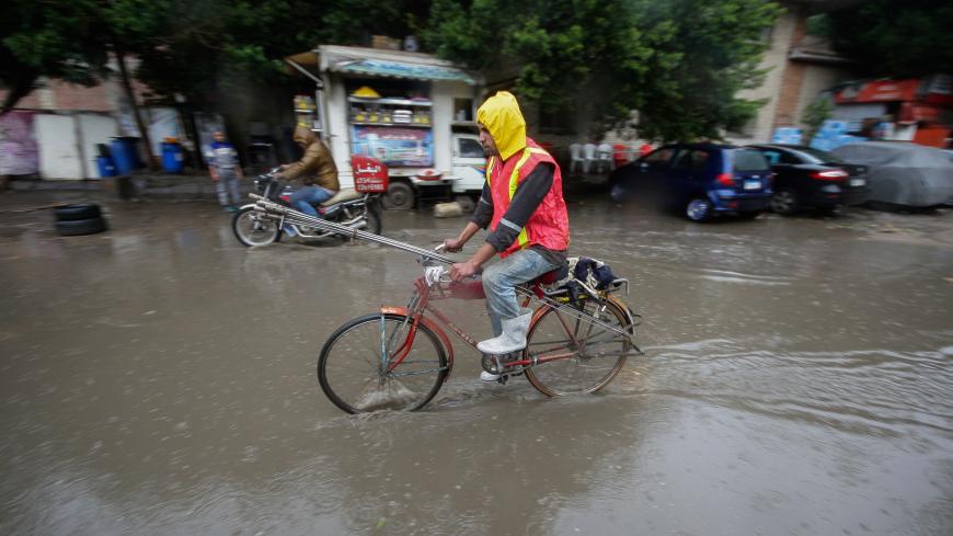 A man rides a bicycle during a thunderstorm and heavy rains in downtown of Cairo, as the government announced a day off while the rain exceeds the infrastructure's capacity in most cities in Egypt March 12, 2020. REUTERS/Shokry Hussien - RC2BIF9XYLHI