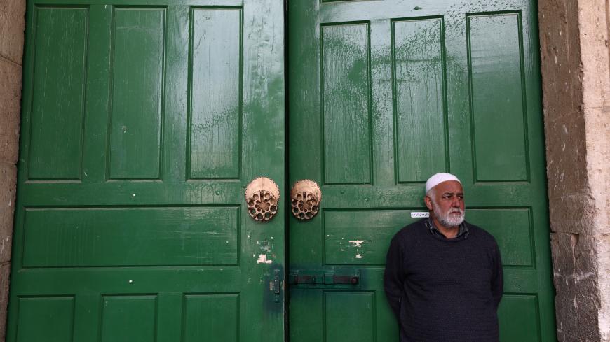 An employee of the Islamic Waqf stands in front of the closed doors of Al-Aqsa mosque in the compound known to Muslims as Noble Sanctuary and to Jews as Temple Mount in Jerusalem's Old City, after Muslim clerics shut the mosque until further notice as a precaution against coronavirus March 15, 2020. REUTERS/Ammar Awad - RC2BKF9DQLY0
