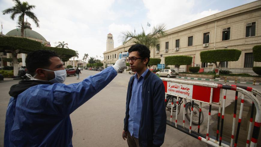 A medical staff member in protective gear checks the temperature of a master's degree student amid concerns over the coronavirus (COVID-19), following the suspension of study for only undergraduate students at Cairo University, to prevent it spreading, in Cairo, Egypt March 15, 2020. REUTERS/Shokry Hussien - RC2GKF96LEH2