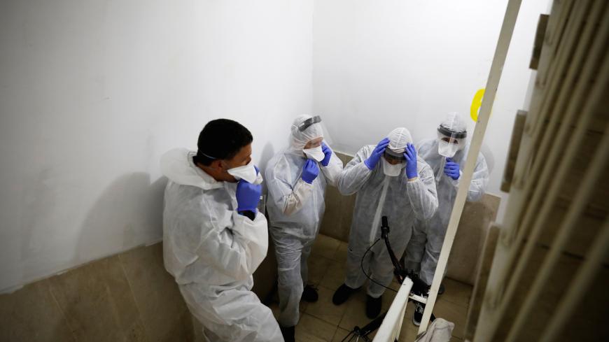 Israeli Health Ministry inspectors put on protective gear before they go up to the apartment of a person in self quarantine as a precaution against coronavirus spread in Hadera, Israel March 16, 2020 REUTERS/Ronen Zvulun - RC23LF9W9DN6