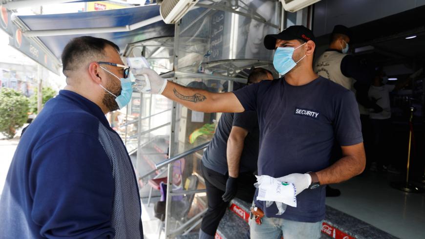 A security man checks the temperature of a customer, as he enters the supermarket before curfew , following the outbreak of coronavirus, in Baghdad, Iraq March 17, 2020. REUTERS/Khalid al-Mousily - RC2RLF917B9G