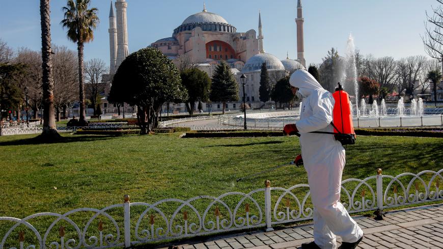 A worker in protective suit disinfects Sultanahmet square in response to the spread of coronavirus disease (COVID-19) in Istanbul,Turkey March 21, 2020. Byzantine-era monument of Hagia Sophia is seen in the background. REUTERS/Kemal Aslan - RC2AOF9OFEM7