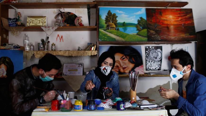 Palestinian artists paint protective face masks to encourage people to wear them as a precaution against the coronavirus disease (COVID-19), in Gaza City March 30, 2020. REUTERS/Mohammed Salem - RC2DUF9EIP84
