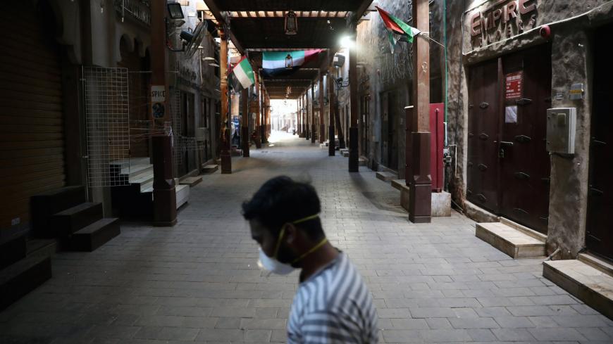 A man wearing a protective face mask walks through the deserted Barajeel Souq, following the outbreak of the coronavirus disease (COVID-19), in old Dubai, United Arab Emirates, March 31, 2020. REUTERS/Christopher Pike - RC25VF9HL1I6