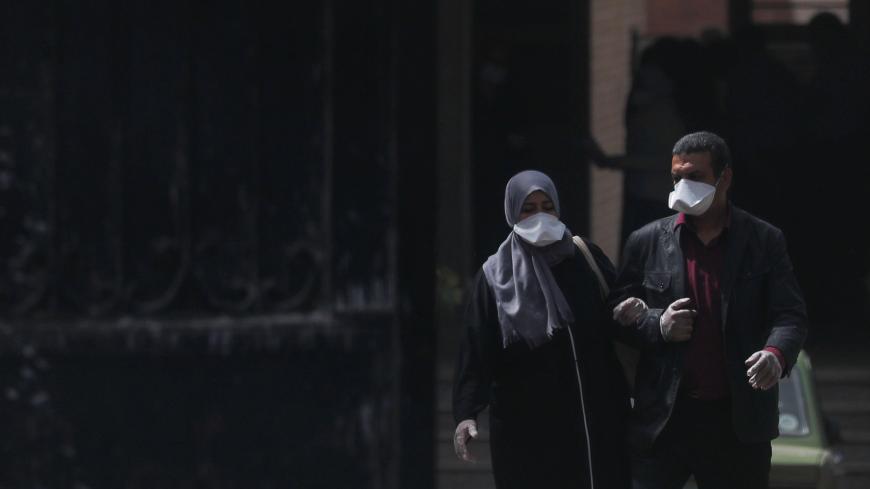 A man and a woman wear protective masks amid concerns over the coronavirus disease (COVID-19) as they walk from the main gate of a hospital in Cairo, Egypt March 31, 2020. REUTERS/Amr Abdallah Dalsh - RC26VF98YX8F
