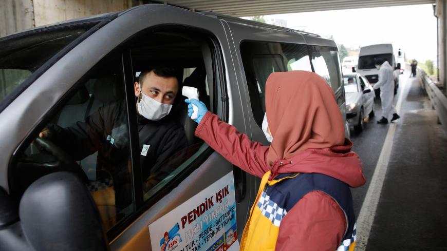 The medic checks the temperature of a driver on a highway near Istanbul after the government decided to shut down the borders of  31 cities for all vehicles excluding transit passage for essential supplies, as the spread of coronavirus disease (COVID-19) continues, at the outskirts of Istanbul, Turkey April 4, 2020. REUTERS/Umit Bektas - RC2RXF9YIECQ