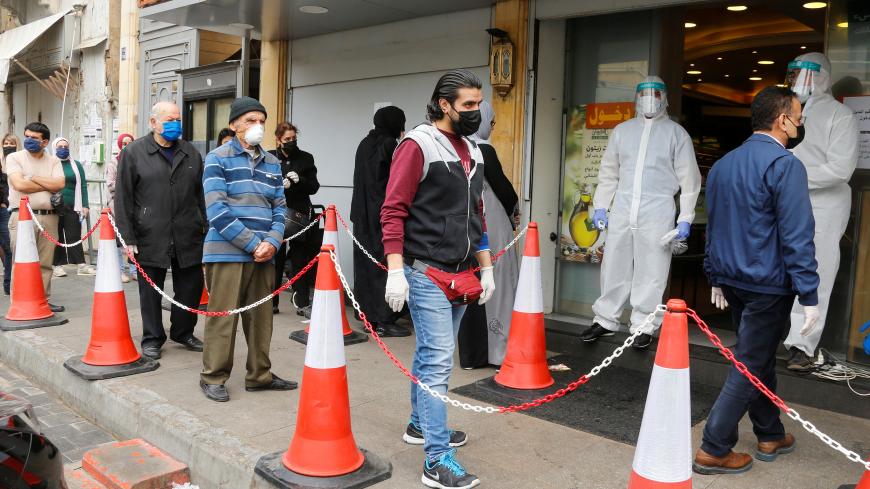 Customers wearing face masks and gloves queue outside a supermarket, during a lockdown to prevent the spread of coronavirus disease (COVID-19) in Beirut, Lebanon April 6, 2020. REUTERS/Mohamed Azakir - RC23ZF91BZ0E