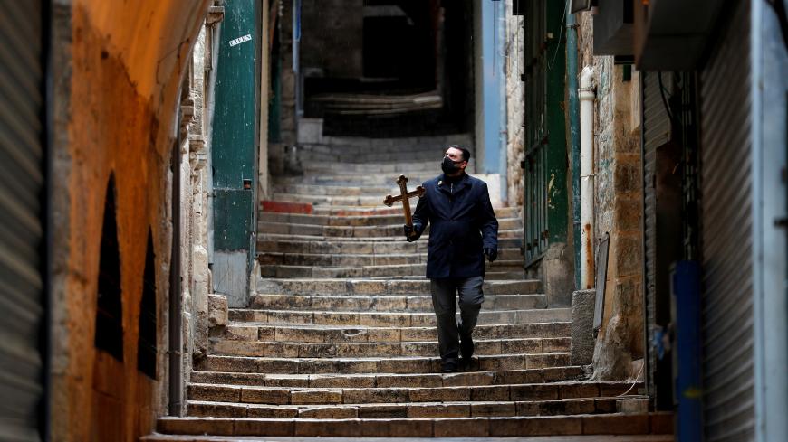 A man carries a cross as he walks the Via Dolorosa on Good Friday amid the coronavirus disease (COVID-19) outbreak, in Jerusalem's Old City April 10, 2020. REUTERS/Ammar Awad     TPX IMAGES OF THE DAY - RC2L1G90HRWF