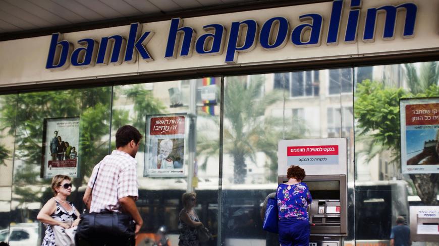 A woman uses an automated teller machine (ATM) outside a Bank Hapoalim branch in Tel Aviv, Israel May 30, 2013.  REUTERS/Nir Elias/File Photo - S1BEUKNLJRAA