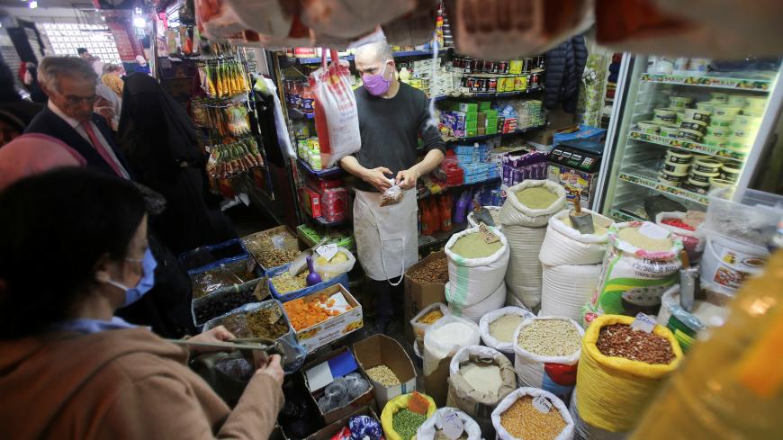 A vendor wearing a protective face mask serves customers inside his shop, ahead of the Muslim holy month of Ramadan, amid concerns over the coronavirus disease (COVID-19), in Algiers, Algeria April 19, 2020. Picture taken April 19, 2020. REUTERS/Ramzi Boudina - RC249G90A84T