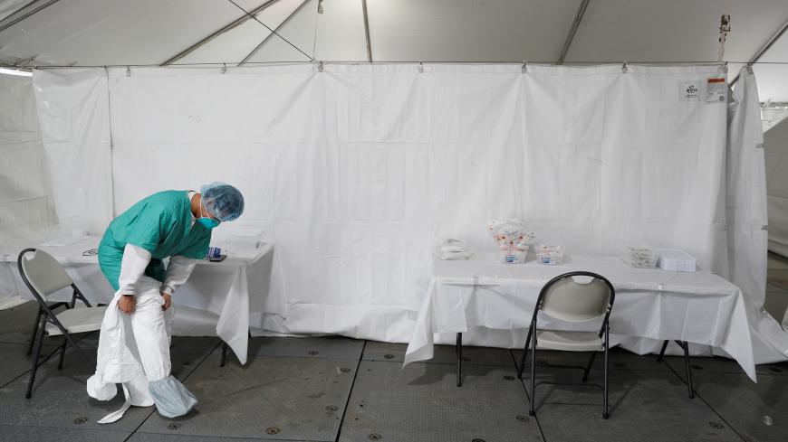 A healthcare worker dons personal protective equipment (PPE) at a One Medical testing facility built to help with the coronavirus disease (COVID-19) outbreak, in the Bronx borough of New York City, U.S., April 21, 2020. REUTERS/Lucas Jackson - RC289G9Z2EGA