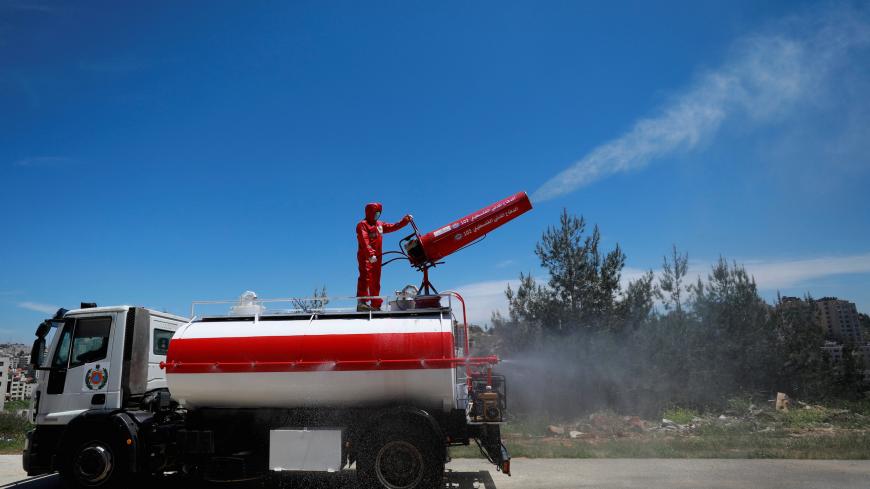 A member of Palestinian Civil Defence on a truck sprays disinfectants during a drill for dealing with coronavirus cases, amid concerns about the spread of the disease (COVID-19), in Ramallah in the Israeli-occupied West Bank April 23, 2020. REUTERS/Mohamad Torokman - RC2BAG918TOA