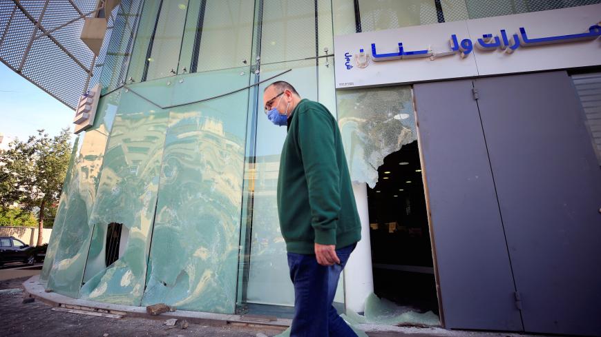 A man wearing a face mask walks past a damaged facade of a bank, after overnight protests fuelled by worsening economic conditions, in the southern city of Sidon, Lebanon April 30, 2020. REUTERS/Ali Hashisho - RC2ZEG9LTAWF