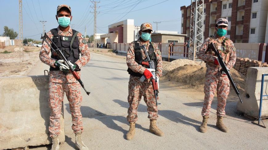TOPSHOT - Soldiers wearing facemasks stand guard on road leading to a quarantine faciltity (R) for people returning from Iran via the Pakistan-Iran border town of Taftan to prevent the spread the COVID-19 coronavirus, in Sukkur in southern Sindh province on March 17, 2020. (Photo by Shahid ALI / AFP) (Photo by SHAHID ALI/AFP via Getty Images)