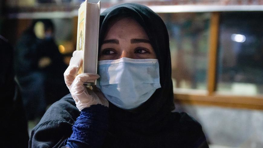 RASHT, IRAN - MAY 15, 2020:
A woman wears a face mask as a preventive measure while holding a Qur'an on her head on the night of laylat al-Qadr during Ramadan amid Coronavirus (COVID-19) crisis.
Every year, Muslims pray on the night of the 21st day of Ramadan known as Lelat al-Qadr by reciting the Qur'an and keeping the Qur'an on their heads. This year despite the coronavirus, people performed religious services in mosques and on the streets.