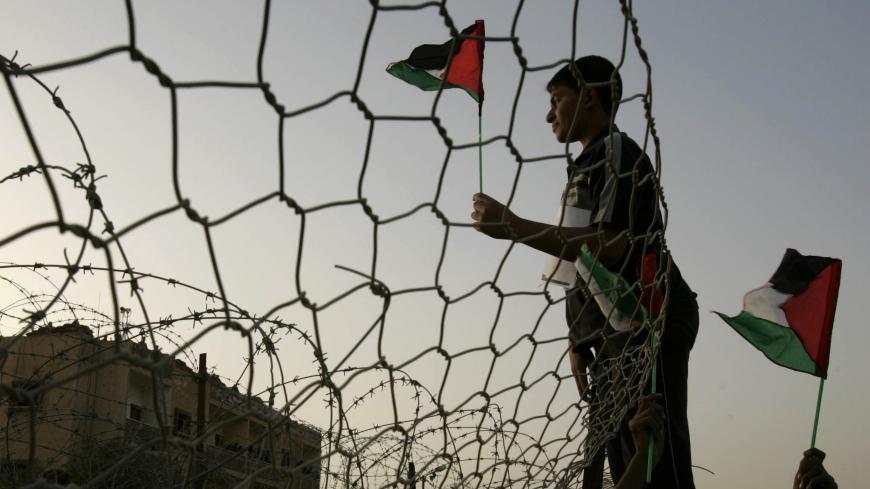 A Palestinian waves the national flag as he stands near the border wall between Egypt and the Gaza Strip, during a protest calling for an end of Israel blockade to the Gaza Strip, April 10, 2008. . REUTERS/Ibraheem Abu Mustafa (GAZA) - GM1E44B08HW02