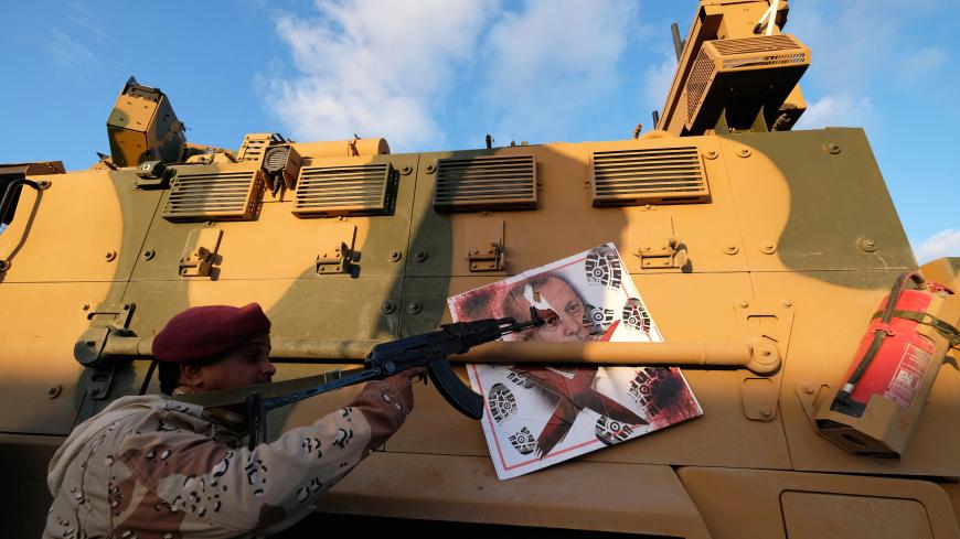 A member of Libyan National Army (LNA) commanded by Khalifa Haftar, points his gun to the image of Turkish President Tayyip Erdogan hanged on a Turkish military armored vehicle, which LNA said they confiscated during Tripoli clashes, in Benghazi, Libya January 28, 2020. REUTERS/Esam Omran Al-Fetori - RC25PE9CSRRF
