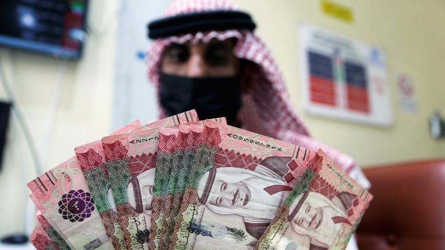 A Saudi money exchanger wears a protective face mask and gloves as he counts Saudi riyal currency at a currency exchange shop in Riyadh, Saudi Arabia March 10, 2020. REUTERS/Ahmed Yosri - RC2ZGF9MUSEW